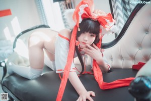 A woman in a red and white outfit sitting on a bed.