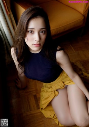 A woman in a white bra and panties sitting on a couch.
