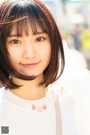 A woman in a white sweater and blue skirt posing for a picture.