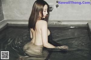 A woman in a bathtub with a black bra and panties.