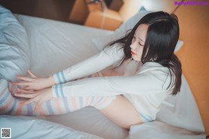 A woman sitting on a bed holding a can of soda.