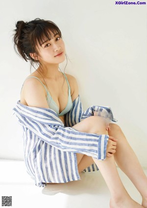 A woman in a blue and white striped shirt is posing for a magazine.