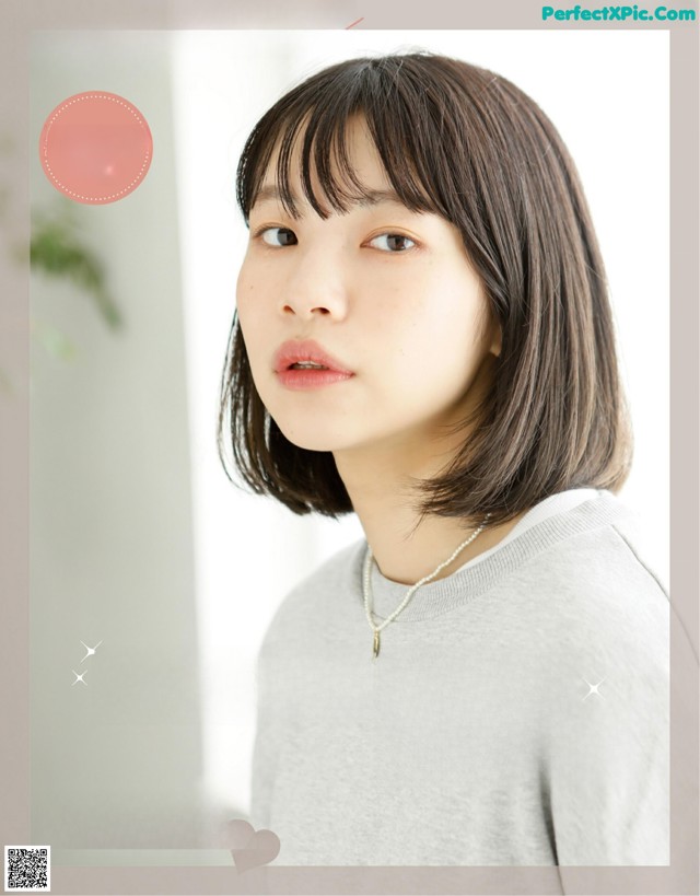 A woman with short brown hair wearing a gray sweater.