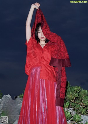 A woman in a black lingerie standing in front of a curtain.