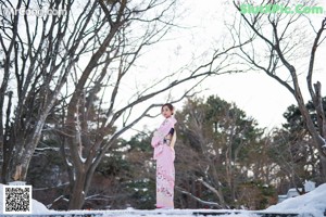 A woman in a pink fur coat standing on a wooden deck.