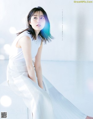 A woman laying on the floor in a white shirt and blue skirt.