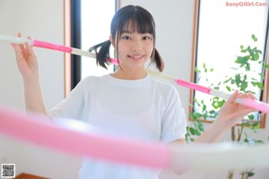 A woman in a white shirt and orange shorts holding a hula hoop.