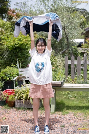 A woman in a white shirt and blue skirt holding a white umbrella.