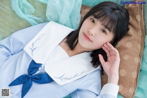 A woman in a school uniform sitting on the floor.