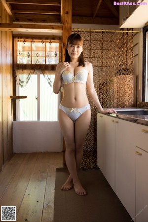 A woman in a white lingerie posing in a kitchen.