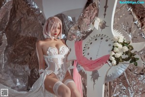 A woman in a white lingerie sitting on a bed.