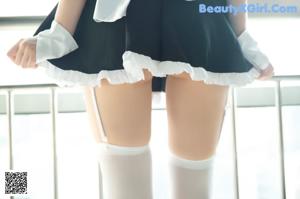A woman in a maid outfit sitting on a chair.