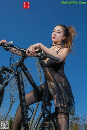 A woman sitting on top of a bike on the side of a road.