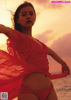 A woman in a red bikini standing on a beach.