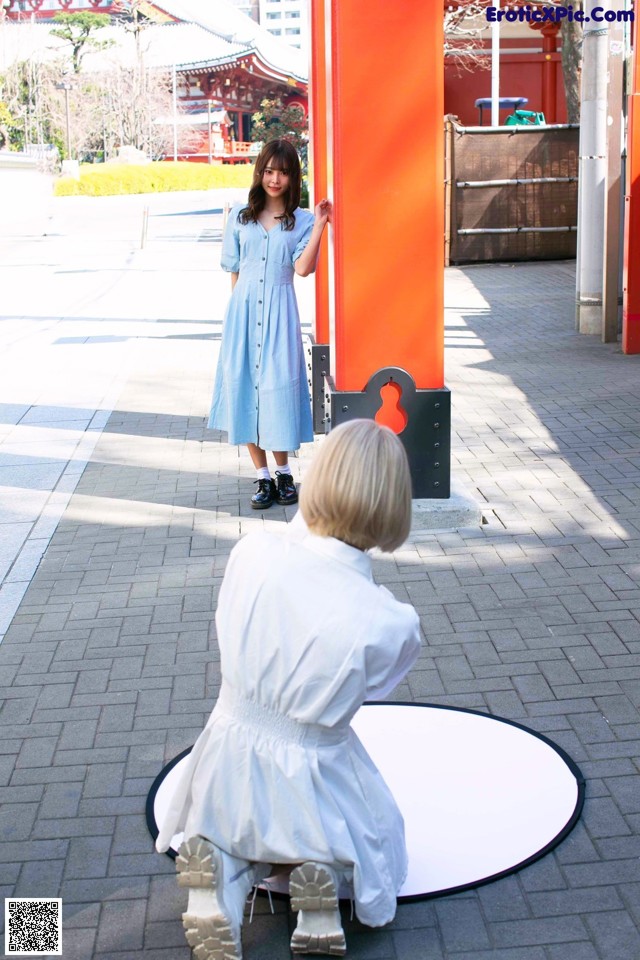 A woman in a blue dress standing next to a red pillar.