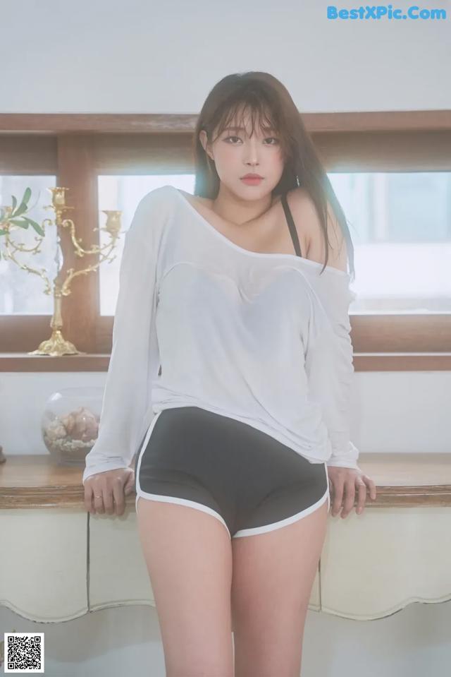 A woman in a white shirt and black shorts posing for a picture.