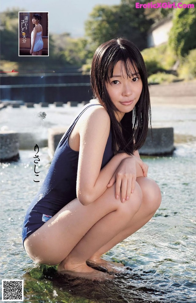 A woman in a blue bathing suit sitting in the water.