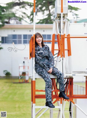 A woman in a military uniform salutes as she stands in front of an airplane.