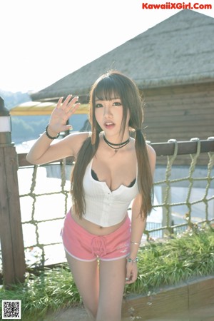 A woman in a white top and pink shorts posing on a bridge.