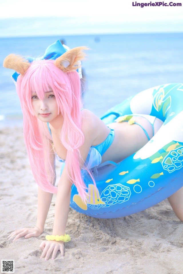 A woman in a bikini laying on an inflatable ring on the beach.