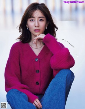A woman in a red sweater writing in a notebook.