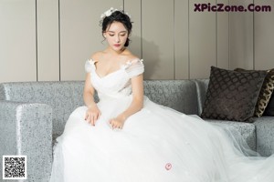 a woman in a white dress sitting on a couch