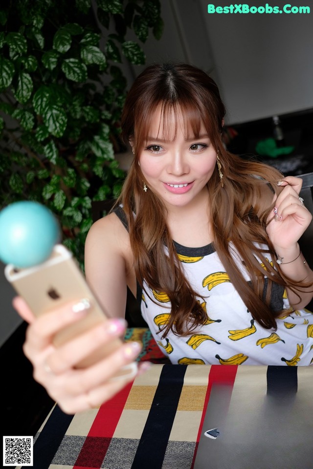 A woman sitting at a table holding a cell phone.