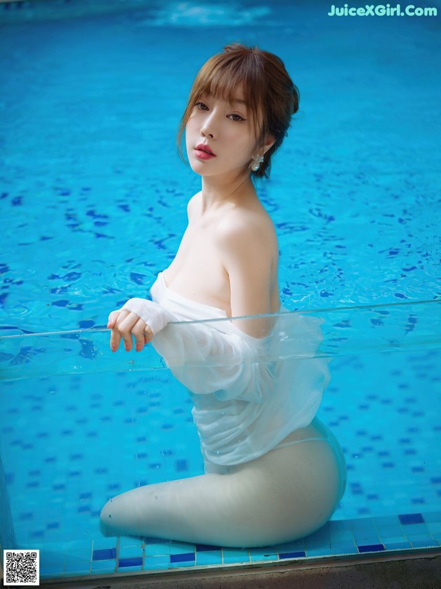 A woman in a white dress sitting in a pool.