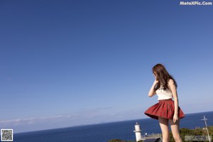 A woman in a red and white plaid skirt standing on a wooden deck.