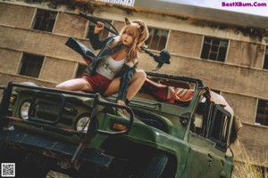 A woman sitting on top of a military vehicle smoking a cigarette.
