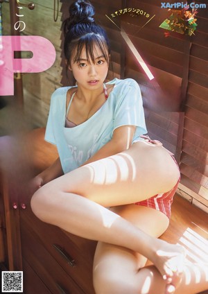 A woman in a blue and white striped bikini looking out of a window.
