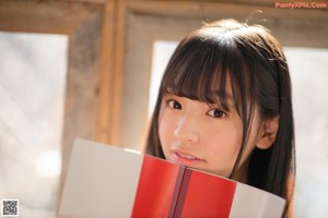 A young woman sitting on a couch reading a book.